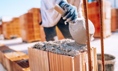 bricklayer-industrial-worker-installing-brick-masonry-on-exterior-wall-with-trowel-putty-knife